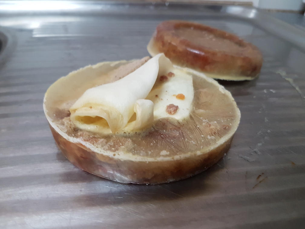 Two frozen ready-to-eat doggy iceblocks. The one in the foreground has a lambs ear sticking out. The one in the background is inverted, so you can see the frozen 'tasty layer' of canned food.